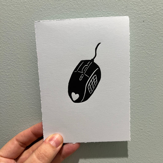 Handmade mini linocut print of an MMO mouse with a heart in black ink on pale blue paper, mirrored left-handed print