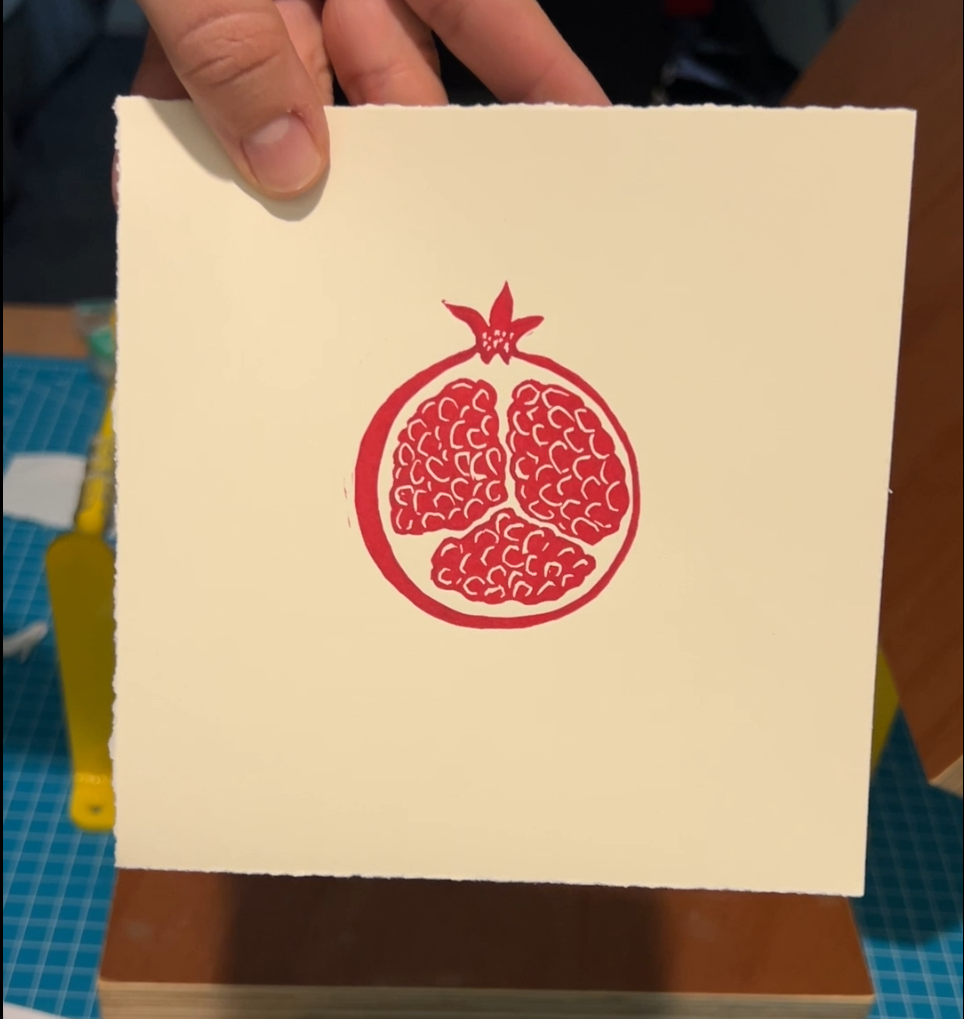 Handmade mini linocut print of a pomegranate in red ink on white paper